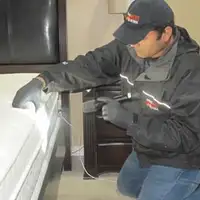 Bed bug inspection technician checking a mattress and bed frame for signs of infestation in Fresno, CA