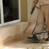 General pest control technician spraying exterior perimeter around a home in Fresno, CA