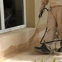 General pest control technician spraying exterior perimeter around a home in Fresno, CA