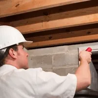 Termite inspection technician checking a basement wall and framing for termite activity in Fresno, CA