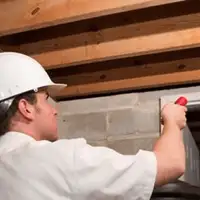 Termite inspection technician checking a basement wall and framing for termite activity in Fresno, CA